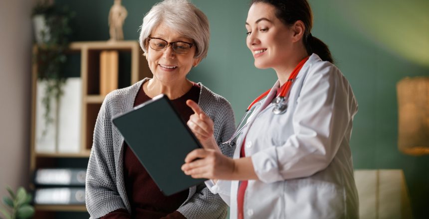 Friendly Doctor Consulting Elderly Patient with Tablet in Office
