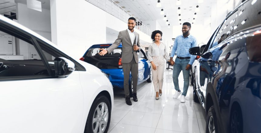 auto in-market, car shoppers, automotive dealership, car salesman speaking to couple browsing for a new car