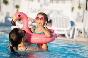 mom and daughter in pool have fun during summer vacation. Child having fun in swimming pool.